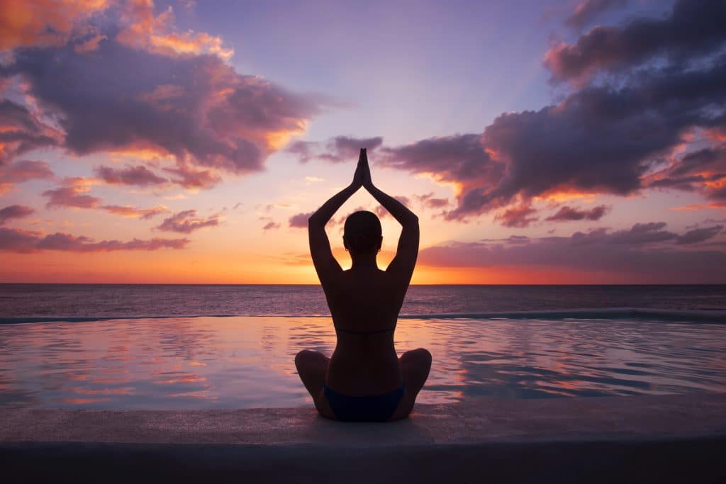 woman doing yoga against setting sun